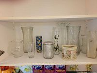 Shelf with ten vases: various clear glass forms, blue mosaic vase, cream ceramic cachepot