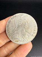 Obverse of coin held between fingers, showing bust of Empress Maria Theresa and surrounding legend