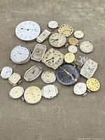 Overhead view of full grouping of watch movements on fabric backdrop