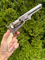 Left side view of engraved replica revolver held in hand