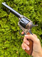 Left side view of metal replica revolver held in hand, showing full length