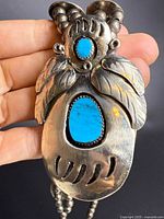 Front view of naja pendant showing turquoise and feather motif