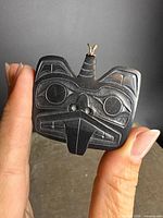 Front view of carved argillite pendant showing design details and gold bail