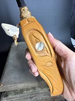 Close view of one cedar handle showing eagle carving and copper inlay