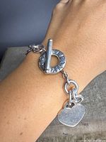 Bracelet worn on wrist showing heart charm and toggle clasp