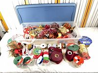Wide shot showing storage bin filled with assorted ribbon rolls and additional rolls arranged in front