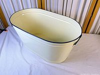 Angled view of pearl white metal oval planter showing exterior and rim accent