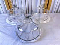 three glass cloches on marble bases