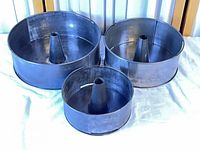 Front view of three nested metal tube cake pans