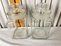 Front view showing both clear glass canisters with lids