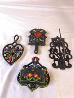 Group shot of all four cast iron trivets showing shapes, painted accents and relative sizes