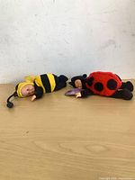 Both Baby Ladybug and Baby Bumblebee dolls lying on surface