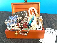 Overall view of open wood box filled with assorted jewelry
