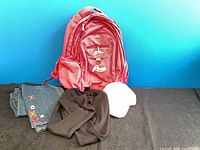 Front view of pink Roots backpack alongside jeans, hat, crop top