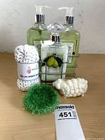 Full lot showing three bath-care bottles in caddy, soap, cloth and scrub pad