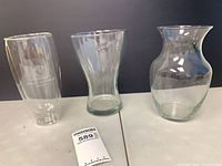 Three clear glass vases on tabletop showing overall shapes