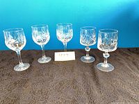 Five crystal wine glasses grouped together showing both patterns