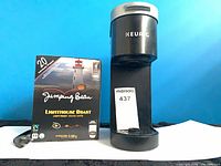 Front view of Keurig brewer beside sealed 20-pack Jumping Bean pods