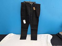 Front view of black Levi’s jeans hung against blue background