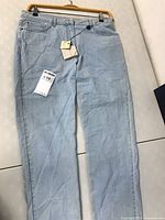 Full view of light blue jeans laid flat showing overall condition and color