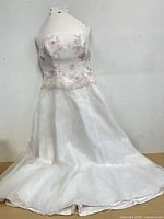 Full view of front of strapless white formal dress with floral appliqué