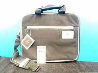 Front view of black Lacoste Parfums laptop bag with tag and shoulder strap