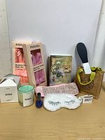 Group shot of entire spa bundle showing candle, two curling rod boxes, eye mask, headband, journal, foot file in burlap bag, nail polish