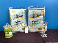 Two sealed Vinni tablecloth packages alongside candle and goblet