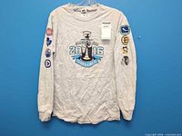 Full front view of grey long-sleeve T-shirt with tournament graphic and sleeve patches