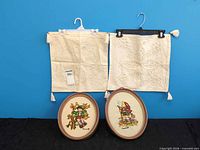 Two pillow shams and two oval framed crewel pieces displayed together