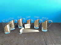 group of six glass cups with metal sleeves and six spoons