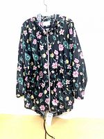 Front view of floral windbreaker showing zipper, snaps, hood drawcord