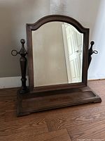 Front view of arched wooden valet mirror on base