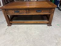 front view of solid wood coffee table showing two drawers, stretcher shelf and legs