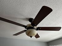 Ceiling fan mounted on ceiling, blades and light kit visible