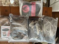Five packaged synthetic hairpieces on table