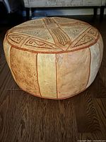 Side view of round leather hassock showing panel construction and wear