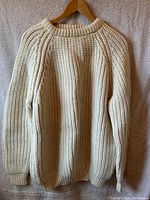 Cream chunky-knit wool pullover on hanger