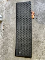 Top view of rectangular black rubber ramp with raised bump texture and brand marking