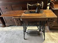 Singer sewing machine open in cabinet showing head and extension leafs