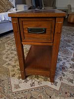 Front view of one side table showing drawer, lower shelf and legs