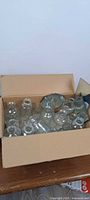 Box containing assorted clear glass small bottles and bud vases