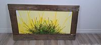 Front view of framed canvas art showing wood frame, painted canvas, and attached faux floral garland