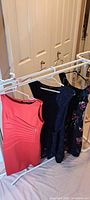 Four dresses hanging on rack: red, dark solid, navy lace, dark floral
