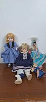 Group of three porcelain-head dolls on wooden surface
