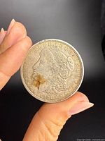 Obverse of 1921 Morgan silver dollar held between fingers showing design details and condition