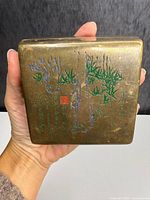 Top view showing engraved enamel bamboo design, calligraphy, red seal