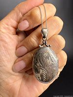 Front view of engraved oval sterling locket on chain