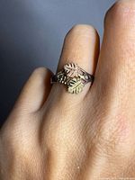ring on hand showing yellow and rose gold leaf details and crossover design