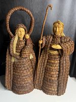 front view of both woven tree toppers showing size, form, carved faces, woven material
